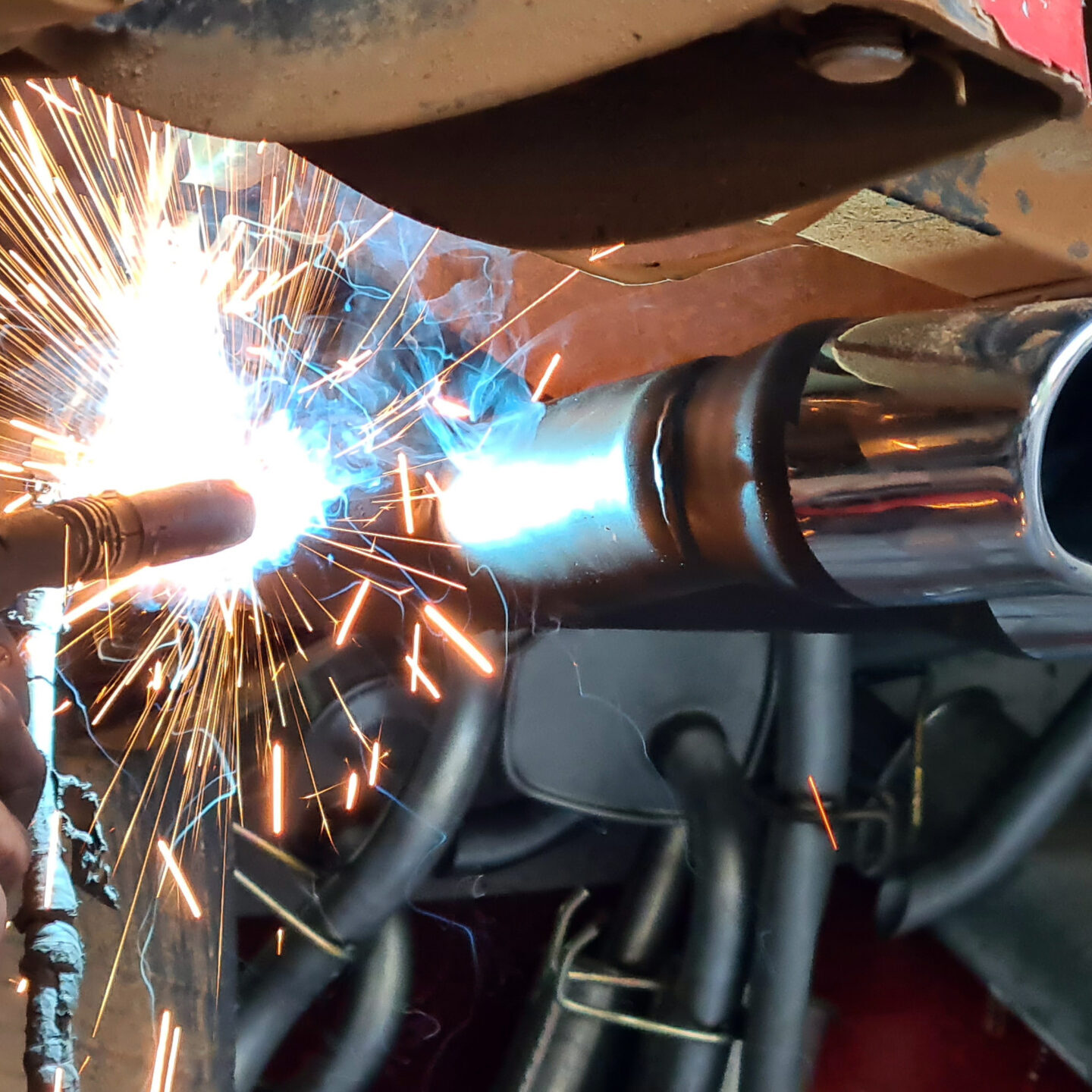 Mechanic or welder is fixing a car exhaust system by welding the exhaust pipe