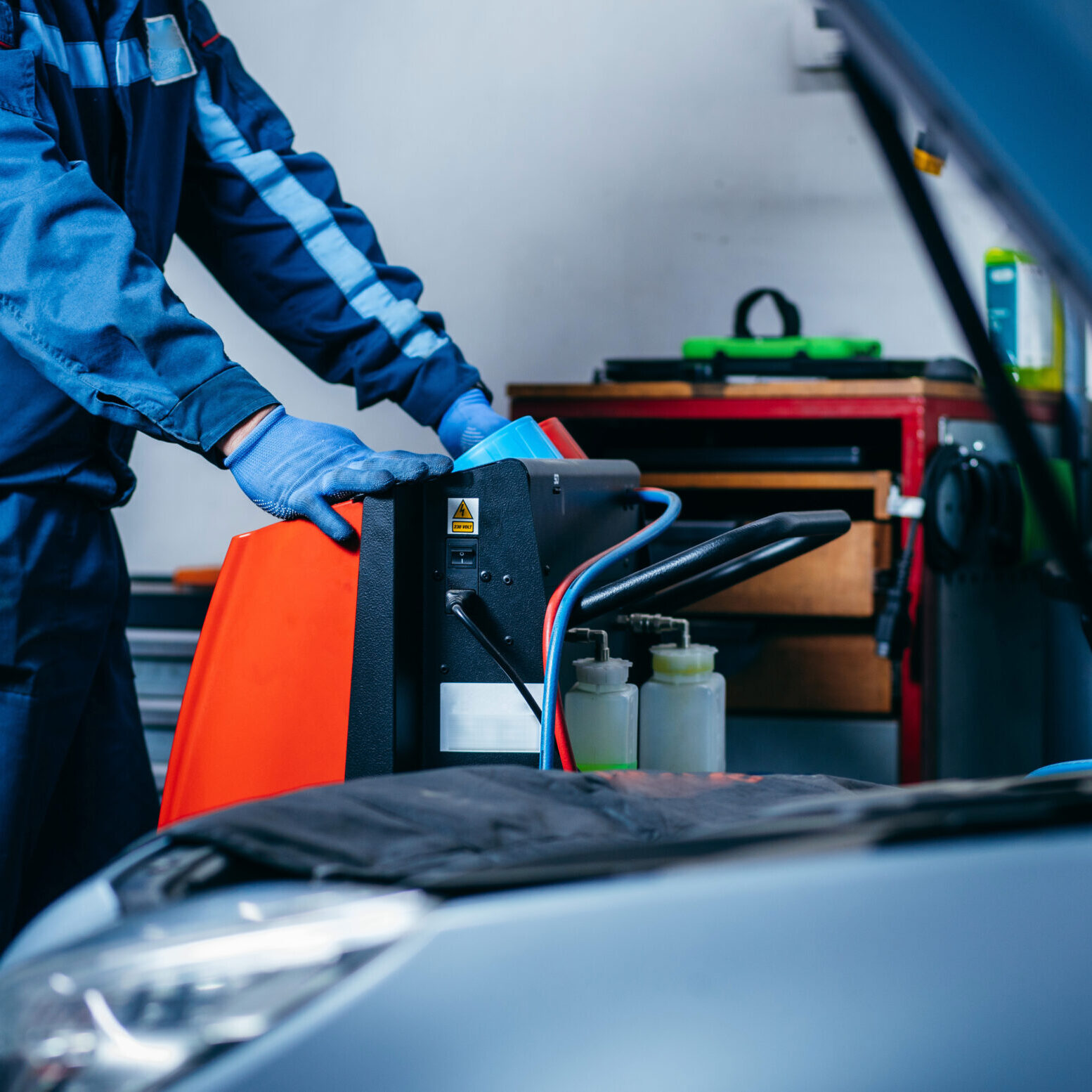 Hands of auto mechanic include the installation of refilling the air conditioner in car service